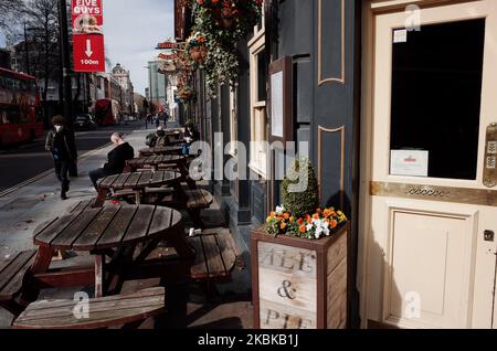 Un uomo che indossa una maschera passa davanti a un pub chiuso in una vicina e deserta Tottenham Court Road a Londra, Inghilterra, il 21 marzo 2020. Gran parte del centro di Londra era praticamente vuota oggi, un giorno dopo che il primo ministro britannico Boris Johnson ordinò la chiusura di tutti i pub, bar, caffè e ristoranti del paese. L'iniziativa rappresenta un inasprimento delle misure volte ad applicare la "distanza sociale” che viene sollecitata ai cittadini a ridurre la crescita delle infezioni da coronavirus 19. Sono stati ordinati anche locali notturni, teatri, cinema, palestre e centri di svago chiusi. Alcuni negozi nel centro della capitale rimasero Foto Stock