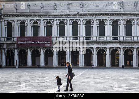 A young kid walking with his mother in a empty S.Mark Square in Venice, Italy, on March 21, 2020. Venice looks totally empty during covid-19 emergency. Almost no people on the streets, except for those waiting to buy food at the supermarkets. (Photo by Giacomo Cosua/NurPhoto) Stock Photo