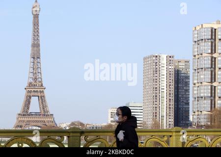 La gente ha visto sul ponte Mirabeau un fronte la Torre Eiffel a Parigi, Francia il 22 marzo 2020, il sesto giorno di una stretta chiusura in Francia mirava a frenare la diffusione del COVID-19, il romanzo coronavirus. A mezzogiorno del 17 marzo 2020 è entrato in vigore un rigido blocco che impone alla maggior parte delle persone in Francia di rimanere a casa, vietando tutte le uscite, tranne quelle essenziali, per frenare la diffusione del coronavirus. Il governo ha detto che decine di migliaia di poliziotti pattuglieranno le strade e commineranno multe di 135 euro (150 dollari) per le persone senza una dichiarazione scritta che giustifichi le loro ragioni di essere fuori. (Phot Foto Stock