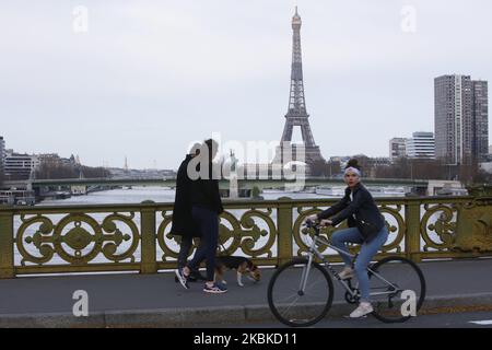 La gente ha visto sul ponte Mirabeau un fronte la Torre Eiffel a Parigi, Francia il 22 marzo 2020, il sesto giorno di una stretta chiusura in Francia mirava a frenare la diffusione del COVID-19, il romanzo coronavirus. A mezzogiorno del 17 marzo 2020 è entrato in vigore un rigido blocco che impone alla maggior parte delle persone in Francia di rimanere a casa, vietando tutte le uscite, tranne quelle essenziali, per frenare la diffusione del coronavirus. Il governo ha detto che decine di migliaia di poliziotti pattuglieranno le strade e commineranno multe di 135 euro (150 dollari) per le persone senza una dichiarazione scritta che giustifichi le loro ragioni di essere fuori. (Phot Foto Stock