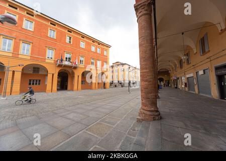 78/5000 A man on a bicycle wearing a mask passes in front of the town hall during COVID-19 pandemic in Italy on March 25, 2020 in Carpi, Italy. (Photo by Emmanuele Ciancaglini/NurPhoto) Stock Photo