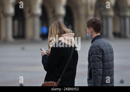 Una giovane coppia che indossa maschere protettive cammina nella Piazza del mercato di Cracovia. Con 1.031 casi confermati di coronavirus e 14 decessi, la situazione della Polonia sta peggiorando giorno per giorno. Il polacco PM Mateusz Morawiecki ha annunciato ieri una serie di nuove restrizioni nel movimento e nei contatti tra le persone. Il regolamento prevede il divieto di lasciare la casa, tranne quando necessario; è consentito andare al lavoro, negozi di alimentari, medici, farmacie e cani da passeggio, come pure brevi passeggiate e formazione sportiva da soli e volontari coinvolti nella lotta contro il coronavirus. Inoltre, non più di due persone s Foto Stock