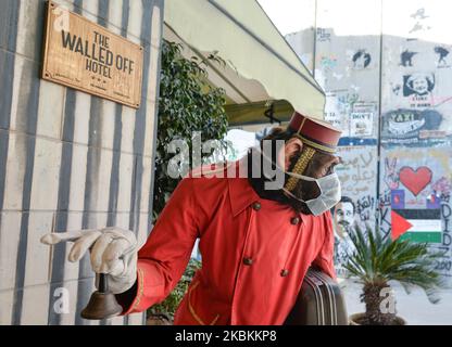 A surgical mask added to the model monkey bellhop at The Walled Off Hotel entrance as coronavirus fears grip residents and tourists. On Thursday, March 5, 2020, in Bethlehem, Palestine (Photo by Artur Widak/NurPhoto) Stock Photo