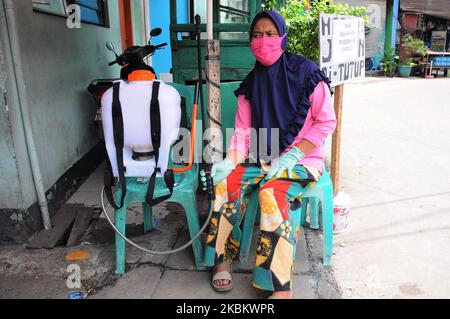 Controlli più stringenti agli ingressi residenziali, i residenti effettuano il check-in e il check-out degli ospiti spruzzando disinfettanti e sono tenuti a lavarsi le mani a Pegangsaan Dua, Jakarta, nell'aprile 1,2020. I residenti con auto-aiuto per rafforzare l'esame all'ingresso della loro residenza mira a rompere la catena di diffusione del COVID-19, a seguito dell'aumento dei pazienti positivi al Covid-19 nella zona di Giacarta. (Foto di Dasril Roszandi/NurPhoto) Foto Stock