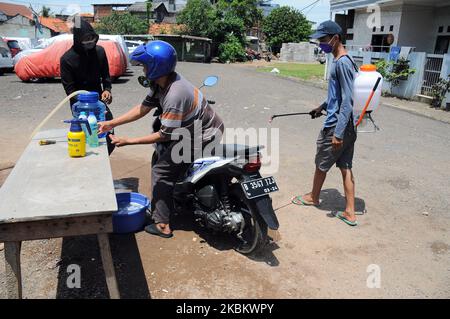 Controlli più stringenti agli ingressi residenziali, i residenti effettuano il check-in e il check-out degli ospiti spruzzando disinfettanti e sono tenuti a lavarsi le mani a Pegangsaan Dua, Jakarta, nell'aprile 1,2020. I residenti con auto-aiuto per rafforzare l'esame all'ingresso della loro residenza mira a rompere la catena di diffusione del COVID-19, a seguito dell'aumento dei pazienti positivi al Covid-19 nella zona di Giacarta. (Foto di Dasril Roszandi/NurPhoto) Foto Stock