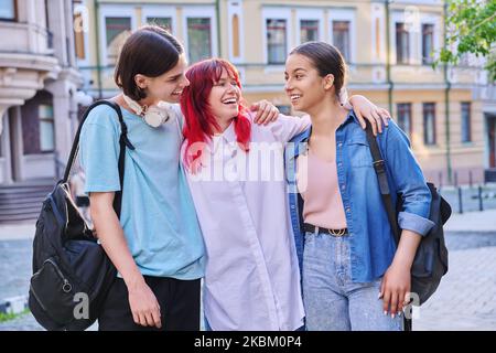 Felice sorridendo abbracciando gli amici adolescenti all'aperto, sulla strada della città Foto Stock