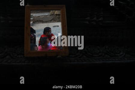 Una donna nepalese che indossa una maschera protettiva si riflette in uno specchio il tredicesimo giorno di blocco nel tentativo di controllare la diffusione di COVID-19 a Bhaktapur , Nepal, Domenica, 5 aprile 2020. (Foto di Saroj Baizu/NurPhoto) Foto Stock