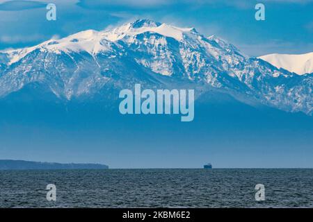 Monte Olimpo innevato come si vede dalla città di Salonicco in Grecia dopo il raro tempo e la nevicata di aprile, la montagna è dietro il mare, il golfo di Thermaikos. Il Monte Olimpo è la montagna più alta della Grecia, con un'altitudine della vetta più alta, Mytikas a 2918m m. Mt. Olimpo fu la casa degli dei greci secondo l'antica mitologia greca. Oggi la montagna è nota per la ricca biodiversità, la ricca flora ed è un Parco Nazionale, il primo in Grecia dal 1938. La montagna è una destinazione estiva ed invernale molto apprezzata per le escursioni, il trekking, l'arrampicata ma anche per i turisti in quanto sono ricchi di f Foto Stock