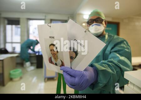 A health professional shows the photographs taken by each worker of the Covadonga hospital so that older people can recognize them despite the masks and protective glasses in Covadonga, Spain, on April 9, 2020. In the most atypical Easter in recent years with the entire population confined at home by the Covid 19 coronavirus pandemic, with the processions suspended throughout Spain and without the possibility of attending mass during these days. In the Covadonga sanatorium they have obtained the necessary permission so that patients with coronavirus can attend the celebration of Holy Thursday  Stock Photo