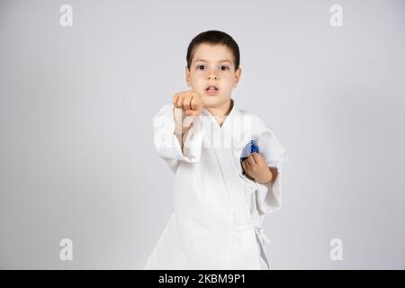 Un ragazzino in kimono pratica il karate, fa pugni con le mani in avanti. Foto Stock