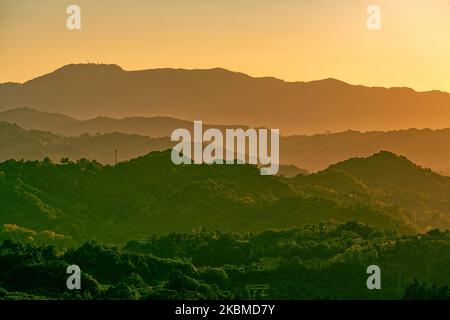 Serie di montagne in controluce illuminate dalla calda luce del tramonto. Italia, Europa Foto Stock