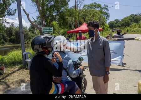 I residenti spruzzano liquido disinfettante e controllano la temperatura corporea sui veicoli utilizzati dai migranti che entreranno nell'area di Kampung Tui, Batam, Isole Riau, 15 aprile 2020. Un certo numero di Kampung tua a Batam ha implementato la quarantena di aree indipendenti come uno sforzo per prevenire e tagliare la diffusione di COVID-19 (Foto di Teguh Prihatna/NurPhoto) Foto Stock