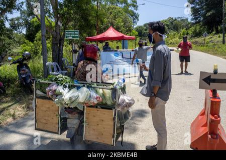 I residenti spruzzano liquido disinfettante e controllano la temperatura corporea sui veicoli utilizzati dai migranti che entreranno nell'area di Kampung Tui, Batam, Isole Riau, 15 aprile 2020. Un certo numero di Kampung tua a Batam ha implementato la quarantena di aree indipendenti come uno sforzo per prevenire e tagliare la diffusione di COVID-19 (Foto di Teguh Prihatna/NurPhoto) Foto Stock