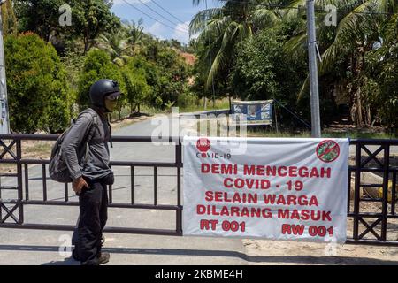 I residenti spruzzano liquido disinfettante e controllano la temperatura corporea sui veicoli utilizzati dai migranti che entreranno nell'area di Kampung Tui, Batam, Isole Riau, 15 aprile 2020. Un certo numero di Kampung tua a Batam ha implementato la quarantena di aree indipendenti come uno sforzo per prevenire e tagliare la diffusione di COVID-19 (Foto di Teguh Prihatna/NurPhoto) Foto Stock