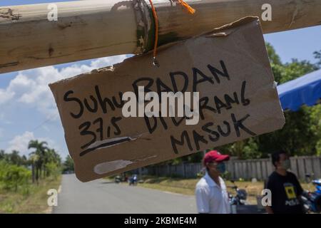 I residenti spruzzano liquido disinfettante e controllano la temperatura corporea sui veicoli utilizzati dai migranti che entreranno nell'area di Kampung Tui, Batam, Isole Riau, 15 aprile 2020. Un certo numero di Kampung tua a Batam ha implementato la quarantena di aree indipendenti come uno sforzo per prevenire e tagliare la diffusione di COVID-19 (Foto di Teguh Prihatna/NurPhoto) Foto Stock