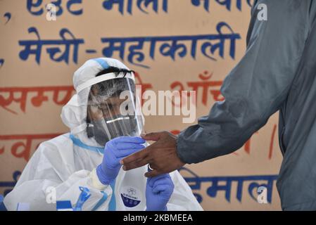 Un operatore sanitario in attrezzatura protettiva prende un campione di sangue da un uomo per un virus Corona (COVID-19) test rapido a Bungamati, Lalitpur, Nepal il Mercoledì, 15 aprile 2020. (Foto di Narayan Maharjan/NurPhoto) Foto Stock