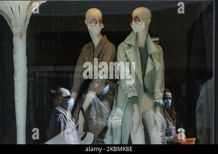 Le persone che indossano maschere protettive passano accanto alla vetrina di un negozio di moda con manichini che indossano maschere mediche, nel centro di Cracovia. Sabato 18 aprile 2020 a Cracovia, Polonia. (Foto di Artur Widak/NurPhoto) Foto Stock