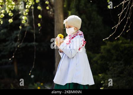 A girl attends the Feast of Mercy at the Sanctuary of the Divine Mercy in Lagiewniki during the spread of coronavirus. Krakow, Poland on 19 April, 2020. The Feast of Divine Mercy established by pope John Paul II is celebrated on the first Sunday after Easter, and that date sees the annual apogee of pilgrimages to the sanctuary. Because of the coronavirus pandemic and according to the ordinance of the state and church authorities, a maximum of five people may attend Mass and services in church. The participants in the Mass have to wait in a line, keeping a safty distance, if they want to pray i Stock Photo