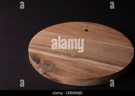 tagliere in legno rotondo con fondo nero Foto Stock