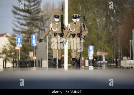 I soldati che indossano maschere facciali sono visti durante il cambio della guardia alla Tomba del Milite Ignoto a Varsavia, Polonia, il 20 aprile 2020. Poiché la Polonia ha raggiunto domenica il picco di nuove infezioni da COVID-19, da quando la prima vittima è stata registrata all'inizio di marzo, il governo sta lentamente alleggerendo le restrizioni sulla vita pubblica consentendo alle persone di utilizzare parchi e foreste. Nelle prossime settimane verrà annunciato un ulteriore allentamento, in quanto il governo è fiducioso che il picco dell'epidemia sarà raggiunto in aprile o all'inizio di maggio. Si prevede che le misure di quarantena provochino un calo del 4-5% del PIL e un doub Foto Stock