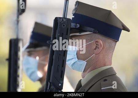 I soldati che indossano maschere facciali sono visti durante il cambio della guardia alla Tomba del Milite Ignoto a Varsavia, Polonia, il 20 aprile 2020. Poiché la Polonia ha raggiunto domenica il picco di nuove infezioni da COVID-19, da quando la prima vittima è stata registrata all'inizio di marzo, il governo sta lentamente alleggerendo le restrizioni sulla vita pubblica consentendo alle persone di utilizzare parchi e foreste. Nelle prossime settimane verrà annunciato un ulteriore allentamento, in quanto il governo è fiducioso che il picco dell'epidemia sarà raggiunto in aprile o all'inizio di maggio. Si prevede che le misure di quarantena provochino un calo del 4-5% del PIL e un doub Foto Stock