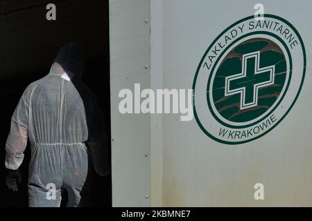 Un lavoratore che indossa tuta protettiva, casco e maschera, raccoglie i bidoni con rifiuti medici presso l'Ospedale Universitario di Cracovia. Martedì 21 aprile 2020 a Cracovia, Polonia. (Foto di Artur Widak/NurPhoto) Foto Stock