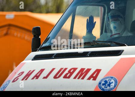 Un operatore medico che indossa tute di nocciola e caschi e maschere di protezione, visto che ondeggiava all'interno di un'ambulanza al di fuori dell'Ospedale Universitario di Cracovia, dopo essere arrivato con un paziente sospettato di essere stato infettato da coronavirus. Martedì 21 aprile 2020 a Cracovia, Polonia. (Foto di Artur Widak/NurPhoto) Foto Stock