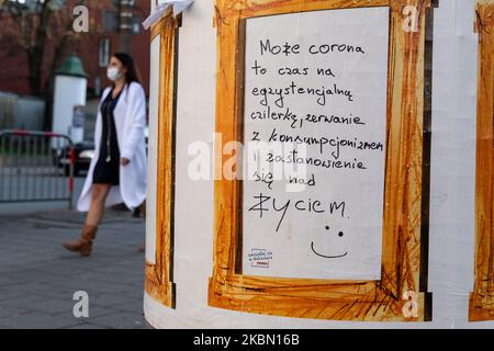 Una donna in maschera protettiva è visto camminare da un poster che incoraggia le persone a prendere tempo e cose sulla loro vita durante la pandemia di Covid-19 a Cracovia, in Polonia, il 27 aprile 2020. Dopo poche settimane di stretta chiusura e distensione sociale causata da Coronavirus diffusione Poles sono nuovamente autorizzati a rilassarsi in spazi aperti, ma deve mantenere la distanza e indossare maschere protettive per il viso in ogni momento, mentre in pubblico. (Foto di Dominika Zarzycka/NurPhoto) Foto Stock