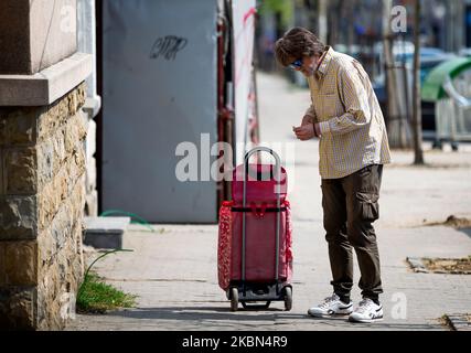 Un vecchio sulla via del ritorno dal mercato si ferma per contare i soldi dopo la riapertura di parrucchieri, palestre, mercati e parchi durante la malattia del coronavirus (COVID-19) a Belgrado, in Serbia, il 30 aprile 2020. Il presidente serbo Aleksandar Vucic aveva dichiarato lo stato di emergenza per fermare la diffusione del coronavirus. Anche il governo ha vietato a tutti gli oltre i 65 anni di lasciare le loro case. A seguito del calo del numero di pazienti con coronavirus il governo di questa settimana permette la riapertura di parrucchieri, palestre, mercati e parchi. (Foto di Nikola Krstic/NurPhoto) Foto Stock