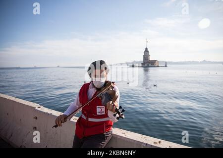 Kä±zÄ±Lay (servizio di aiuto umanitario in Turchia) operaio suona violino in una strada costiera vuota intorno alla Torre di Maiden a Istanbul, Turchia il 01 maggio 2020. La Turchia ha adottato una serie di misure per prevenire la diffusione del virus, tra cui la chiusura di scuole, ristoranti e altri spazi pubblici. Ci sono anche coprifuoco tutto il giorno del fine settimana in 31 città tra cui Istanbul, con un blocco di tre giorni dal 1 maggio, una festa pubblica. (Foto di CEM TekkeÅŸinoÄŸlu/NurPhoto) Foto Stock