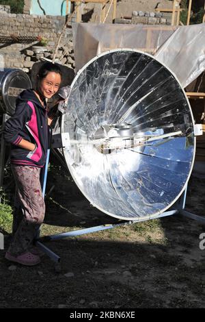 La ragazza Ladakhi usa un fornello solare parabolico per riscaldare l'acqua per il tè fuori della sua casa nel piccolo villaggio di Tangtse, Ladakh, Jammu e Kashmir, India. (Questa immagine ha un modello firmato disponibile) (Foto di Creative Touch Imaging Ltd./NurPhoto) Foto Stock