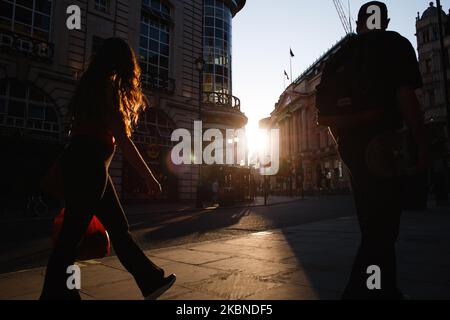 La gente cammina lungo un Haymarket quasi deserito al tramonto a Londra, Inghilterra, il 6 maggio 2020. La Gran Bretagna è ormai ben entrata nella sua settima settimana di blocco del coronavirus, anche se si prevede che questa domenica sarà annunciato un leggero allentamento delle restrizioni, insieme a un calendario per ulteriori 'agevolazioni' nei prossimi mesi. Secondo le cifre attuali del Dipartimento della Salute e dell'assistenza sociale del Regno Unito, i decessi di Covid-19 in tutto il paese hanno raggiunto nel frattempo 30.076. La cifra è attualmente considerata la più alta in Europa, anche se gli esperti hanno avvertito che potrebbe essere qualche mese prima di un accurato comp Foto Stock