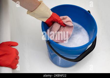 la mano toglie uno straccio bagnato da un secchio d'acqua Foto Stock