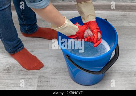 donna che strizzava uno straccio bagnato in un secchio Foto Stock