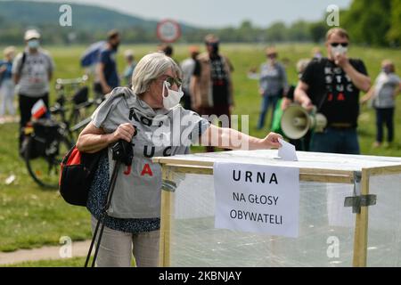 Un attivista del Comitato per la Difesa della democrazia (KOD) esprime il suo voto durante una finta elezione al Blonia Park di Cracovia. Le elezioni si sono svolte oggi, ma sono state sospese in seguito a un dibattito su come e quando si poteva votare in modo sicuro durante la pandemia di coronavirus. Il governo aveva proposto un voto a carattere postale, ma le critiche al piano e i complicati preparativi hanno portato al rinvio annunciato solo mercoledì scorso. Domenica 10 maggio 2020 a Cracovia, Polonia. (Foto di Artur Widak/NurPhoto) Foto Stock