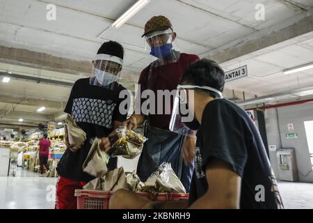 Mercanti di mercato che indossano maschera facciale e scudo mentre acquistano alimenti in mezzo alla malattia di coronavirus (COVID-19) pandemia nel mercato tradizionale di Denpasar, Bali, Indonesia il 15 2020 maggio. Il governo della città ha annunciato protocolli sanitari che ogni mercante deve indossare maschera, visiera protettiva e guanti per prevenire la diffusione della malattia di coronavirus. (Foto di Johanes Christo/NurPhoto) Foto Stock