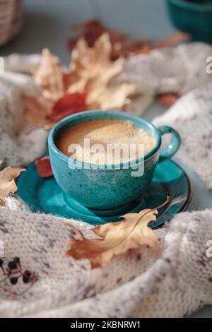 White knitted scarf, blue cup of coffee and dry yellow leaves Stock Photo