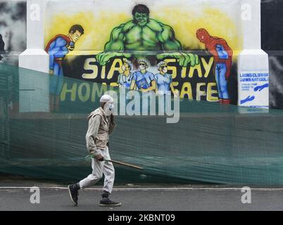 Un uomo che indossa una maschera facciale passa davanti a un murale con un messaggio che raffigura super eroi immaginari chiedendo di prendere precauzioni contro il coronavirus, durante il blocco COVID-19 in corso, a Guwahati, Assam, India Venerdì 15 maggio, 2020. (Foto di David Talukdar/NurPhoto) Foto Stock