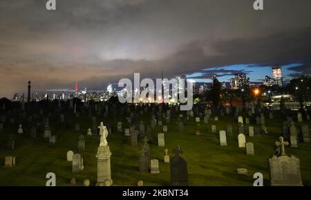 Le lapidi sono viste in un cimitero di New York City sullo sfondo dei grattacieli di Manhattan, Stati Uniti il 13 maggio 2020. (Foto di Selcuk Acar/NurPhoto) Foto Stock