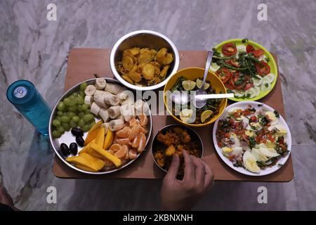 Spuntini e frutta sono tenuti per rompere velocemente da un uomo musulmano a Gurugram nella periferia di Nuova Delhi, India il 17 maggio 2020. (Foto di Nasir Kachroo/NurPhoto) Foto Stock