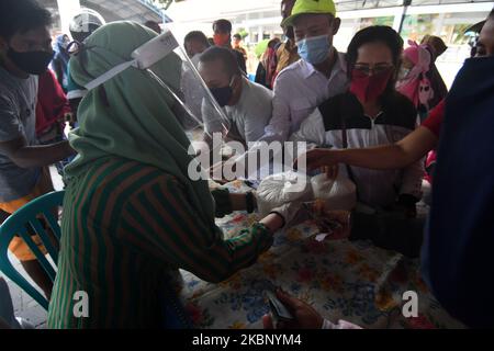 I residenti acquistano prodotti alimentari che vengono venduti all'apertura di un mercato a buon mercato a Palu, nella Provincia Centrale di Sulawesi, Indonesia, il 18 maggio 2020. Il mercato è detenuto dal governo locale ogni anno poco prima di Lebaran e la vendita di ingredienti alimentari a prezzi bassi è imballato con residenti anche se il virus corona è pandemico (COVID-19). (Foto di Mohamad Hamzah/NurPhoto) Foto Stock