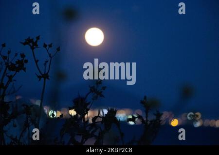 Lo scintillante Super Flower Moon del maggio 2020, visto che sorge sul Mar Egeo e sulla città di Salonicco in Grecia da Kalochori il 7 maggio 2020. L'ascesa dell'ultima superluna del 2020 appare sulle colline della città di Salonicco, brilla nel cielo greco-mediterraneo e si riflette sul mare illuminando la notte oscura. (Foto di Nicolas Economou/NurPhoto) Foto Stock