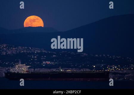 Lo scintillante Super Flower Moon del maggio 2020, visto che sorge sul Mar Egeo e sulla città di Salonicco in Grecia da Kalochori il 7 maggio 2020. L'ascesa dell'ultima superluna del 2020 appare sulle colline della città di Salonicco, brilla nel cielo greco-mediterraneo e si riflette sul mare illuminando la notte oscura. (Foto di Nicolas Economou/NurPhoto) Foto Stock