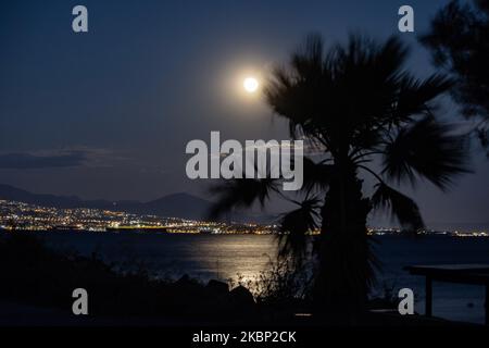 Lo scintillante Super Flower Moon del maggio 2020, visto che sorge sul Mar Egeo e sulla città di Salonicco in Grecia da Kalochori il 7 maggio 2020. L'ascesa dell'ultima superluna del 2020 appare sulle colline della città di Salonicco, brilla nel cielo greco-mediterraneo e si riflette sul mare illuminando la notte oscura. (Foto di Nicolas Economou/NurPhoto) Foto Stock