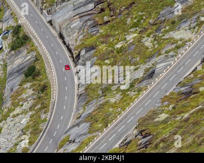 Auto rossa singola sul passo di Grimsel, pendii settentrionali sopra il lago Grimsel, Svizzera Foto Stock