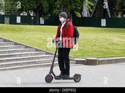 A man wearing a protective mask amid the Covid-19 coronavirus epidemic rides on an electric scooter on a street in Kyiv, Ukraine, on 24 May, 2020. As on 24 May 2020 in Ukraine in total 20,986 laboratory-confirmed cases of the coronavirus COVID-19, including 617 fatal, according the Ukraine's Ministry of Health website. (Photo by STR/NurPhoto) Stock Photo