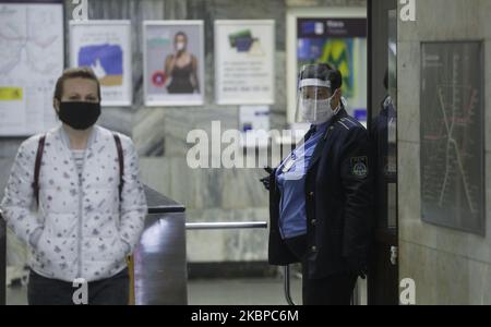 A woman with her face mask on walks past an Underground employee with a shield on, as she passes a map as she walks through the Underground entrance turnstile in Kyiv, Ukraine, May 28, 2020. Ukrainian Cabinet of Ministers has introduced so-called adaptive quarantine across the country from 22 May, in which the applicable strictness of the quarantine measures delegated to regional authorities (Photo by Sergii Kharchenko/NurPhoto) Stock Photo