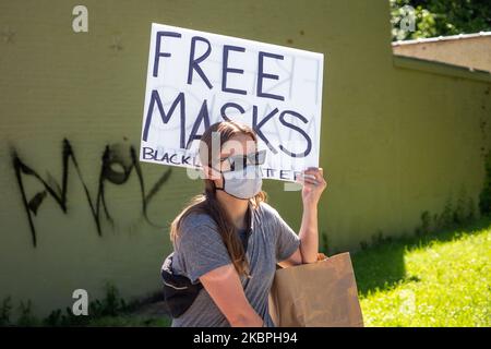 Una donna tiene in mano un segno che offre maschere gratuite per prevenire il Coronavirus e COVID-19 durante una protesta della morte di George Floyd, domenica 31 maggio 2020, a Cincinnati, Ohio, Stati Uniti. (Foto di Jason Whitman/NurPhoto) Foto Stock