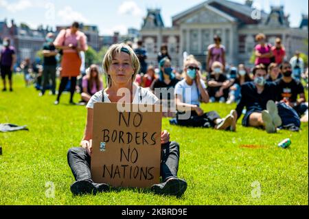 Una donna è seduta sull'erba, mentre tiene un cartello pro rifugiati, durante la manifestazione Refugee Lives Matter ad Amsterdam, nei Paesi Bassi, il 20th giugno 2020. (Foto di Romy Arroyo Fernandez/NurPhoto) Foto Stock