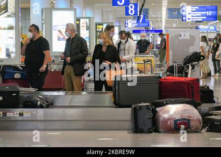 Passeggeri visti con le maschere facciali obbligatorie all'aeroporto internazionale ATH LGAV di Atene, in Grecia, il 18 giugno 2020, dopo la quarantena di Coronavirus e le restrizioni di viaggio. I passeggeri che indossano maschere e guanti, utilizzano disinfettanti per le mani come misura preventiva contro la diffusione della pandemia COVID-19. La Grecia e l'Europa hanno chiuso a lungo le frontiere per le persone al di fuori dell'Europa e della zona Schengen, ma la Grecia ha iniziato a revocare il divieto di circolazione dal 15 giugno 2020 per i paesi della zona Schengen e il 1 luglio 2020 si arriverà a un maggiore allentamento. I passeggeri in arrivo sono soggetti al decor Foto Stock